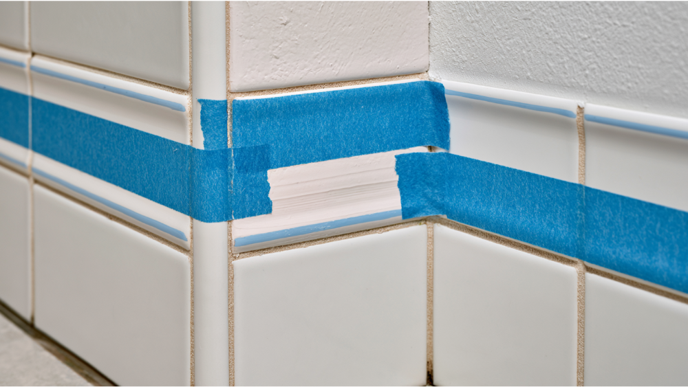 Applying color-matched epoxy to repair a small chip in a ceramic floor tile.