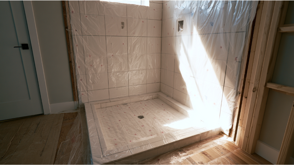 Professional waterproof membrane installation inside a modern walk-in shower before installing wall and floor tiles.
