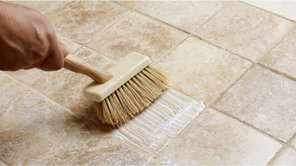 Soft brush cleaning grout lines between travertine tiles with a pH-neutral natural stone cleaner.