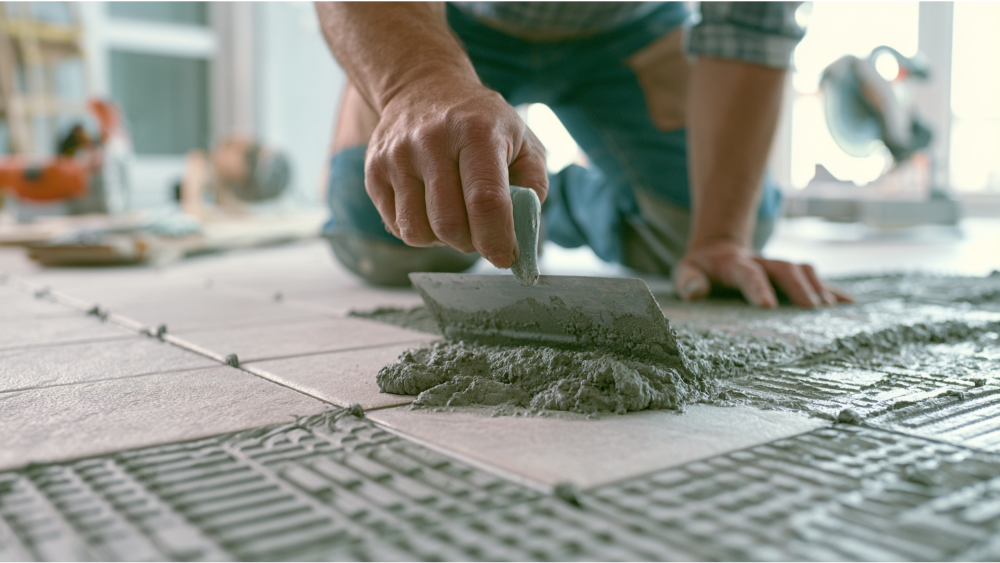 Installing porcelain floor tiles with thinset mortar using a notched trowel and tile spacers.